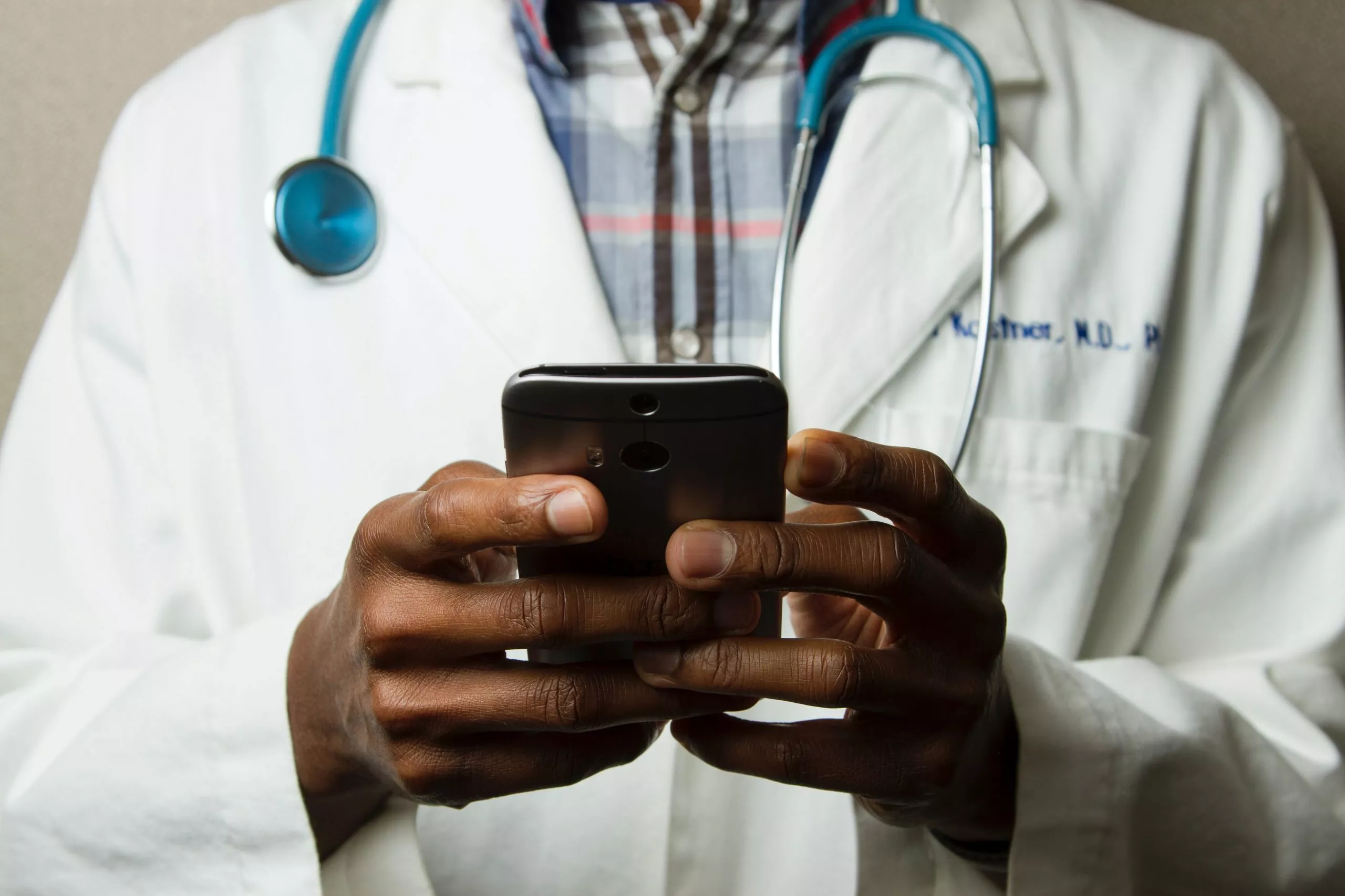 Black male doctor holding cell phone